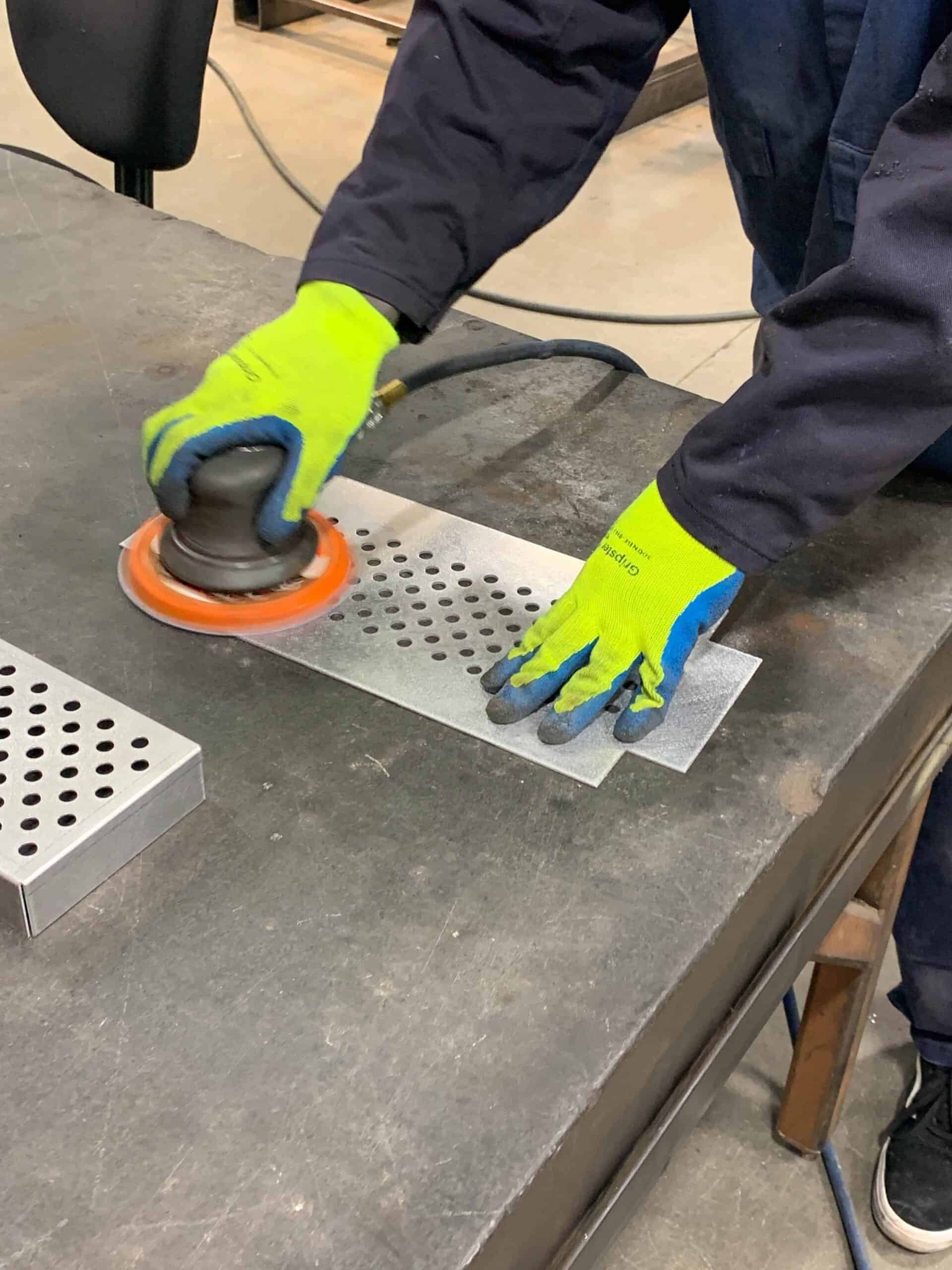 a man deburring a small metal frame that was pressed